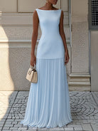 NEWYORKLISTED STYLE COLLECTION: Woman wearing a light blue dress with pleated skirt standing on a stone pavement.