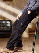 NEWYORKLISTED ATLAS MEN's COLLECTION: Person wearing black cargo pants sitting on a stool indoors.