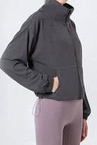 NEWYORKLISTED ACTIVEWEAR COLLECTION: Person wearing a dark gray jacket and light purple leggings on a white background