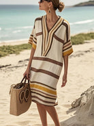 NEWYORKLISTED STYLE COLLECTION: Woman in a striped beach cover-up with a straw bag on a sandy beach.