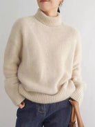 Person wearing a beige sweater and blue jeans against a plain background NEWYORKLISTED STYLE COLLECTION