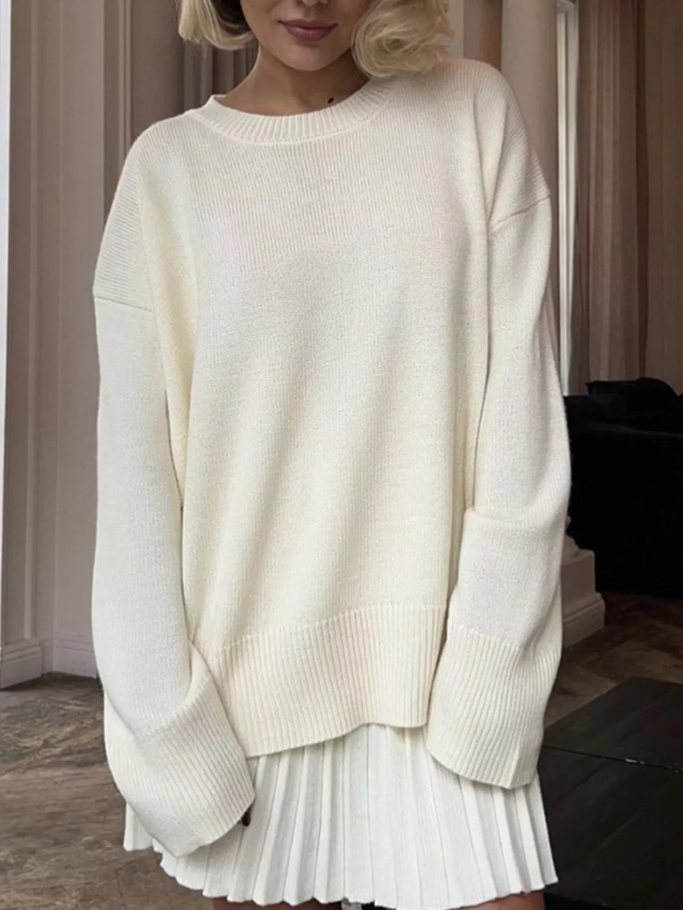 NEWYORKLISTED STYLE COLLECTION: Person wearing a white sweater and pleated skirt indoors.