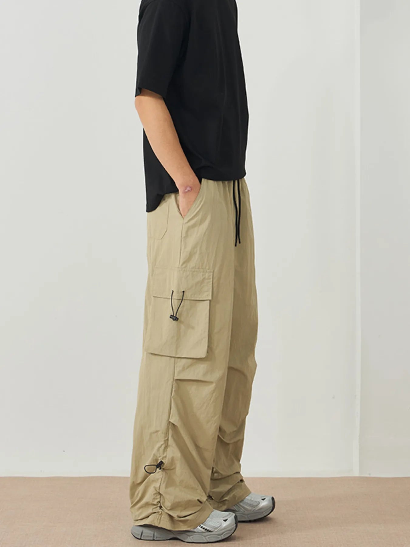 NEWYORKLISTED ATLAS MEN's Collection: Person wearing beige cargo pants and a black top against a white background