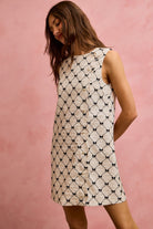 NEWYORKLISTED STYLE COLLECTION: Woman wearing a patterned dress against a pink background