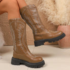 NEWYORKLISTED SHOE COLLECTION: Round Toe Block Heels Boots: Brown cowboy boots with detailed stitching worn by a person sitting on a textured surface.