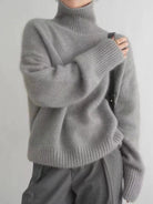 Person wearing a gray turtleneck sweater against a plain background