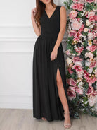 NEWYORKLISTED STYLE COLLECTION: Woman wearing a black dress with a slit standing next to a floral arrangement.
