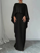 NEWYORKLISTED STYLE COLLECTION: Woman wearing a black pleated dress with a draped top against a neutral background