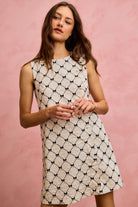 NEWYORKLISTED STYLE COLLECTION: Woman wearing a sleeveless dress with a geometric pattern against a pink background