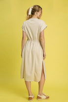 NEWYORKLISTED STYLE COLLECTION: Short Sleeve Midi Tee Dress: Woman wearing a beige dress with a yellow background