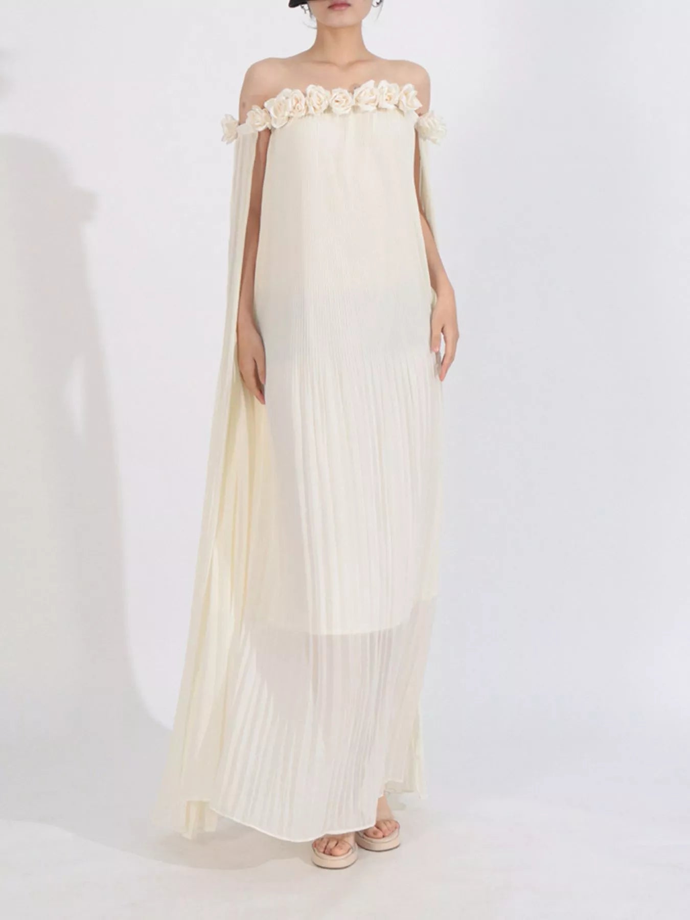 NEWYORKLISTED STYLE COLLECTION: Woman wearing a white off-shoulder dress with floral details on a white background