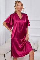 NEWYORKLISTED Intimate Apparel: Woman wearing a pink satin nightgown in a room with white walls and furniture.