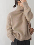Person wearing a beige turtleneck sweater with a plain background
