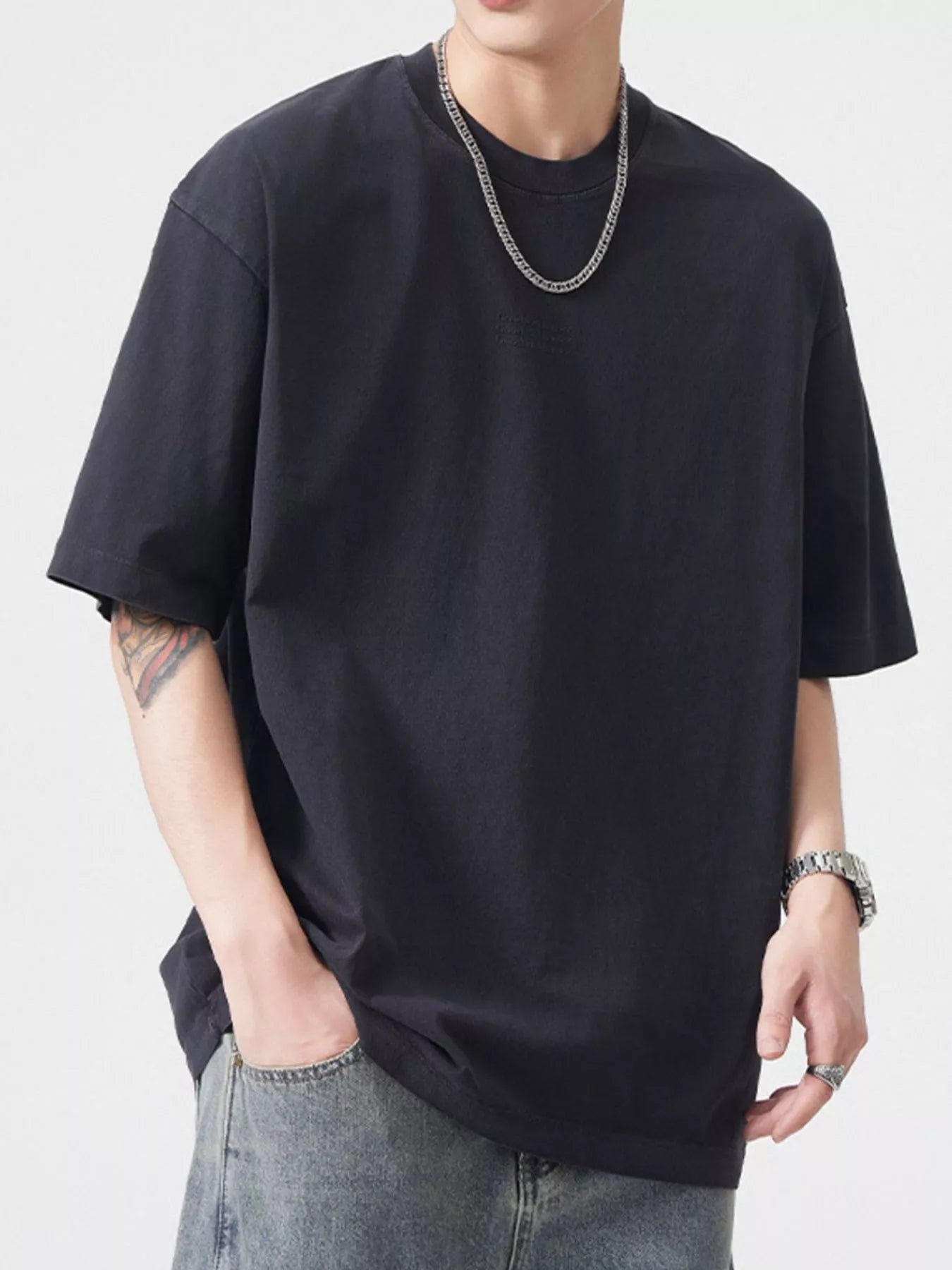 NEWYORKLISTED ATLAS MEN's COLLECTION: Person wearing a black t-shirt and jeans with a plain background