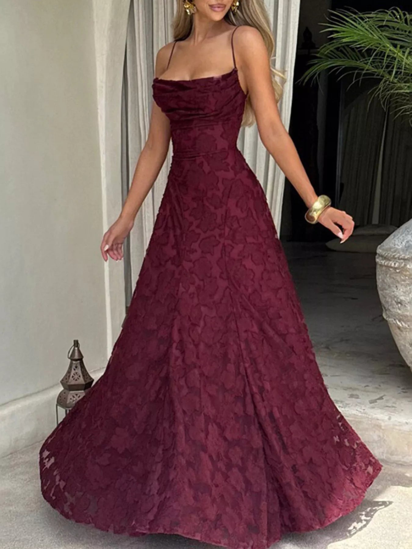 NEWYORKLISTED STYLE COLLECTION: Woman wearing a burgundy lace evening gown indoors.