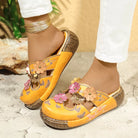 NEWYORKLISTED SHOE COLLECTION: Yellow sandals with floral designs worn by a person on a stone surface.