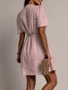 NEWYORKLISTED STYLE COLLECTION: Woman wearing a pink lace dress holding a book against a plain background