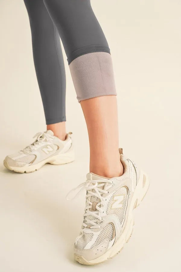 NEWYORKLISTED ACTIVEWEAR Person wearing light-colored sneakers and gray leggings on a neutral background showing the fleece lining on the leggings