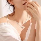 NEWYORKLISTED Valentine’s Day Specials: Woman wearing a delicate necklace with a heart-shaped pendant, set against a soft background.