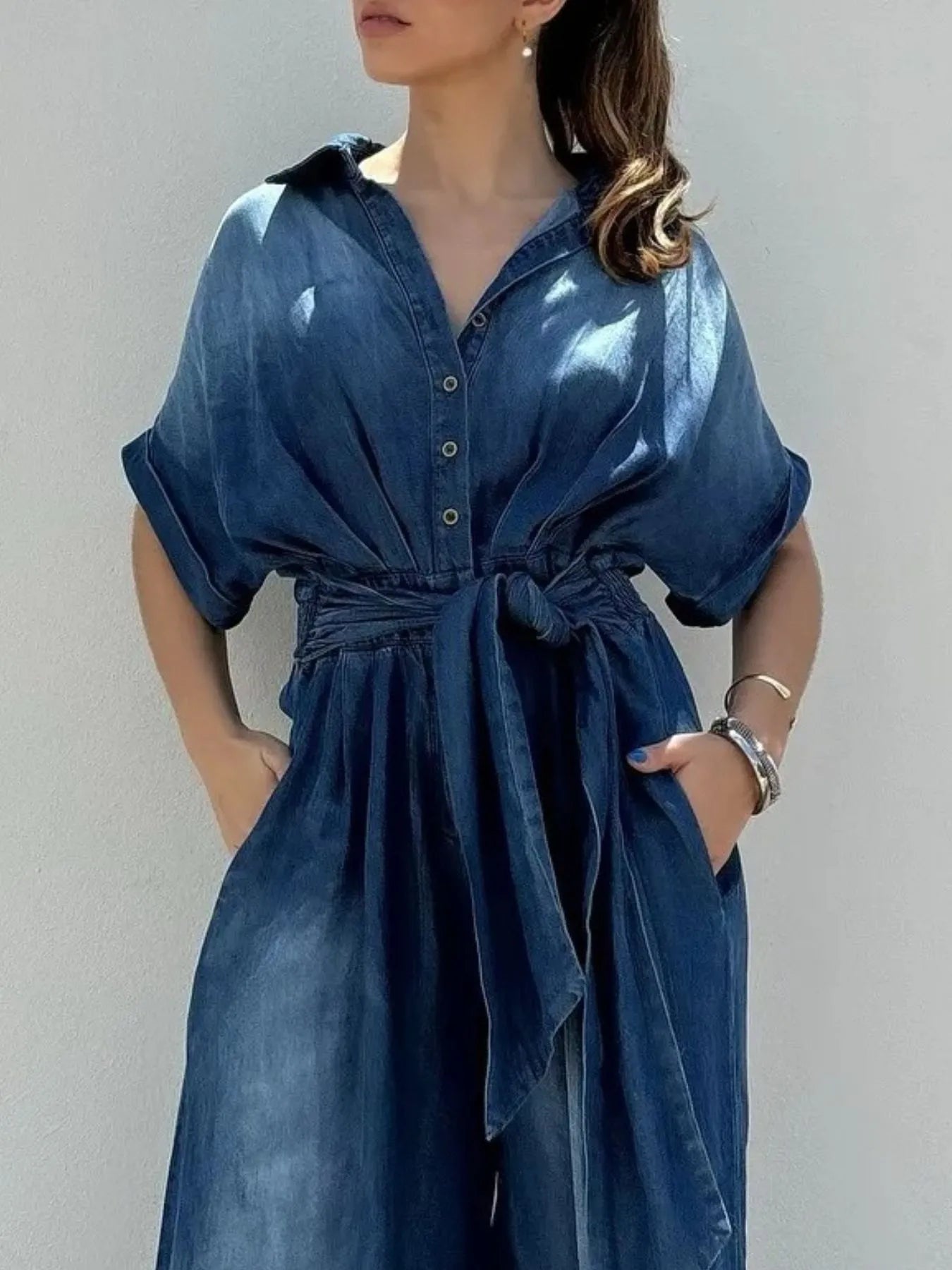 NEWYORKLISTED STYLE COLLECTION: Woman wearing a blue denim dress against a plain background