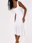 NEWYORKLISTED STYLE COLLECTION: A woman modeling a white sleeveless midi dress with a square neckline, ruched waist, and flared hem against a plain white background.