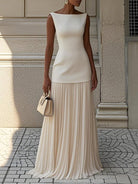 NEWYORKLISTED STYLE COLLECTION: Woman wearing a long beige dress standing on a stone pavement.
