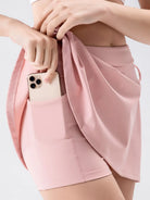 NEWYORKLISTED ACTIVEWEAR COLLECTION: Person wearing a pink skirt with a phone in the pocket on a light gray background