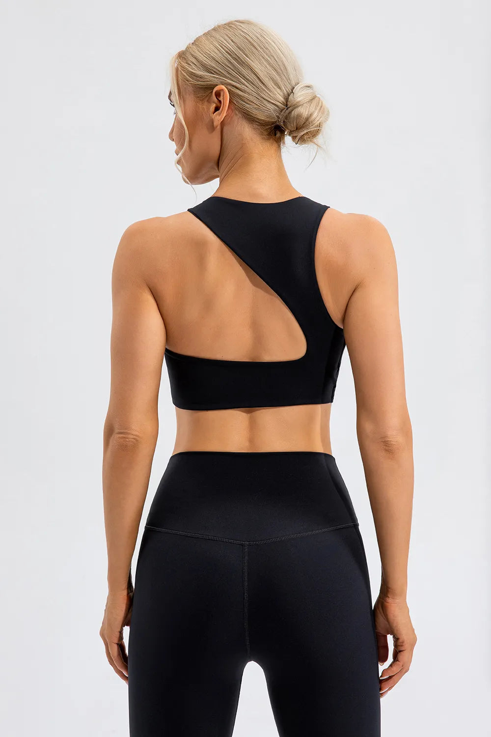 NEWYORKLISTED ACTIVEWEAR COLLECTION: Person wearing a black sports bra and leggings on a light gray background