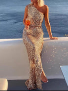 NEWYORKLISTED STYLE COLLECTION: Woman in a sparkly gold dress by the ocean holding a drink.