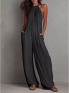 NEWYORKLISTED STYLE COLLECTION: Woman wearing a dark gray jumpsuit against a plain background