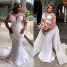 Woman in a white beaded wedding dress holding flowers indoors.