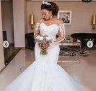 Woman in a white wedding dress holding flowers in a room.