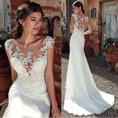 Woman wearing a white lace wedding dress in an outdoor setting.
