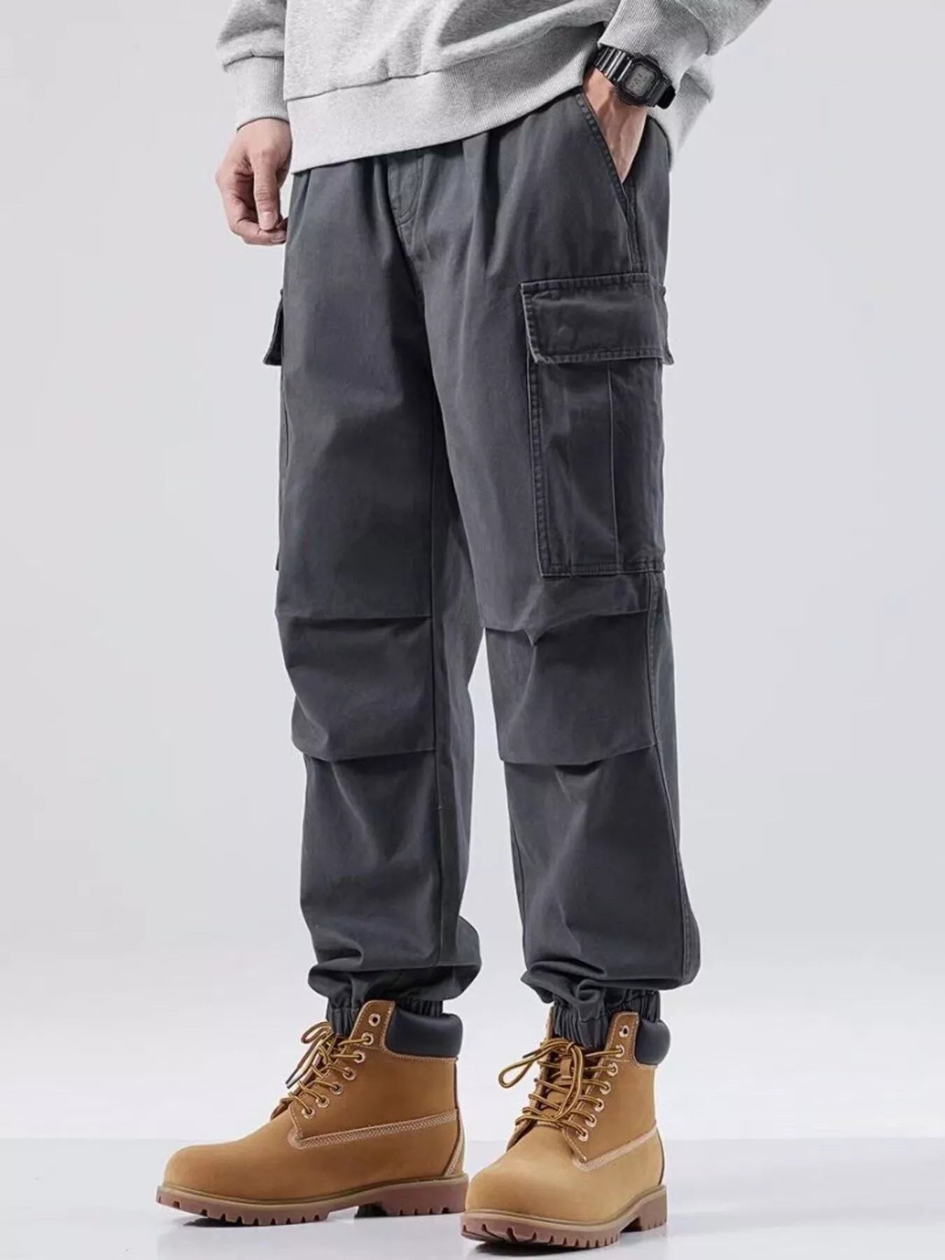 NEWYORKLISTED ATLAS MEN'S COLLECTION: Person wearing gray cargo pants and tan boots on a white background