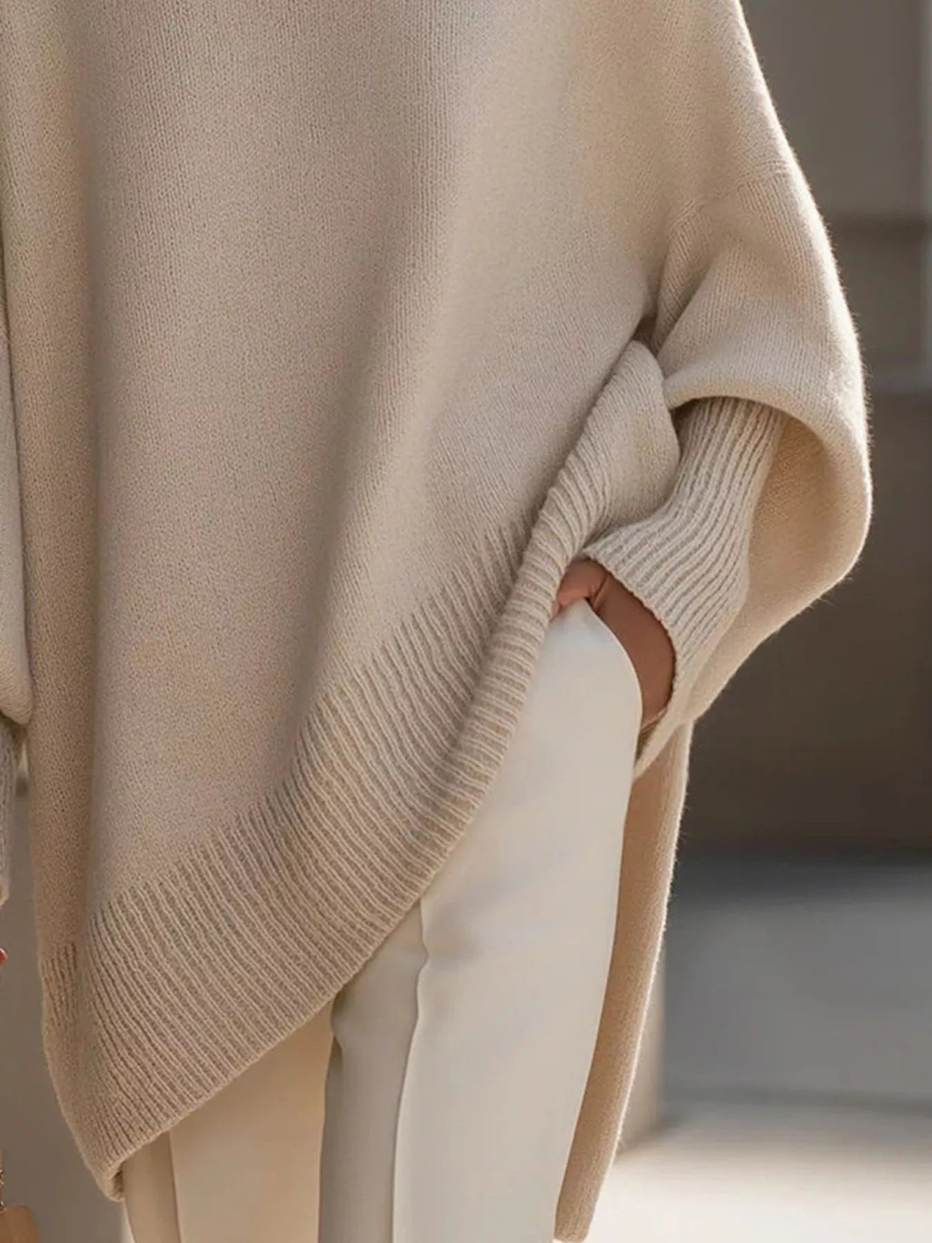 NEWYORKLISTED STYLE COLLECTION: Beige sweater draped over a surface with a blurred background