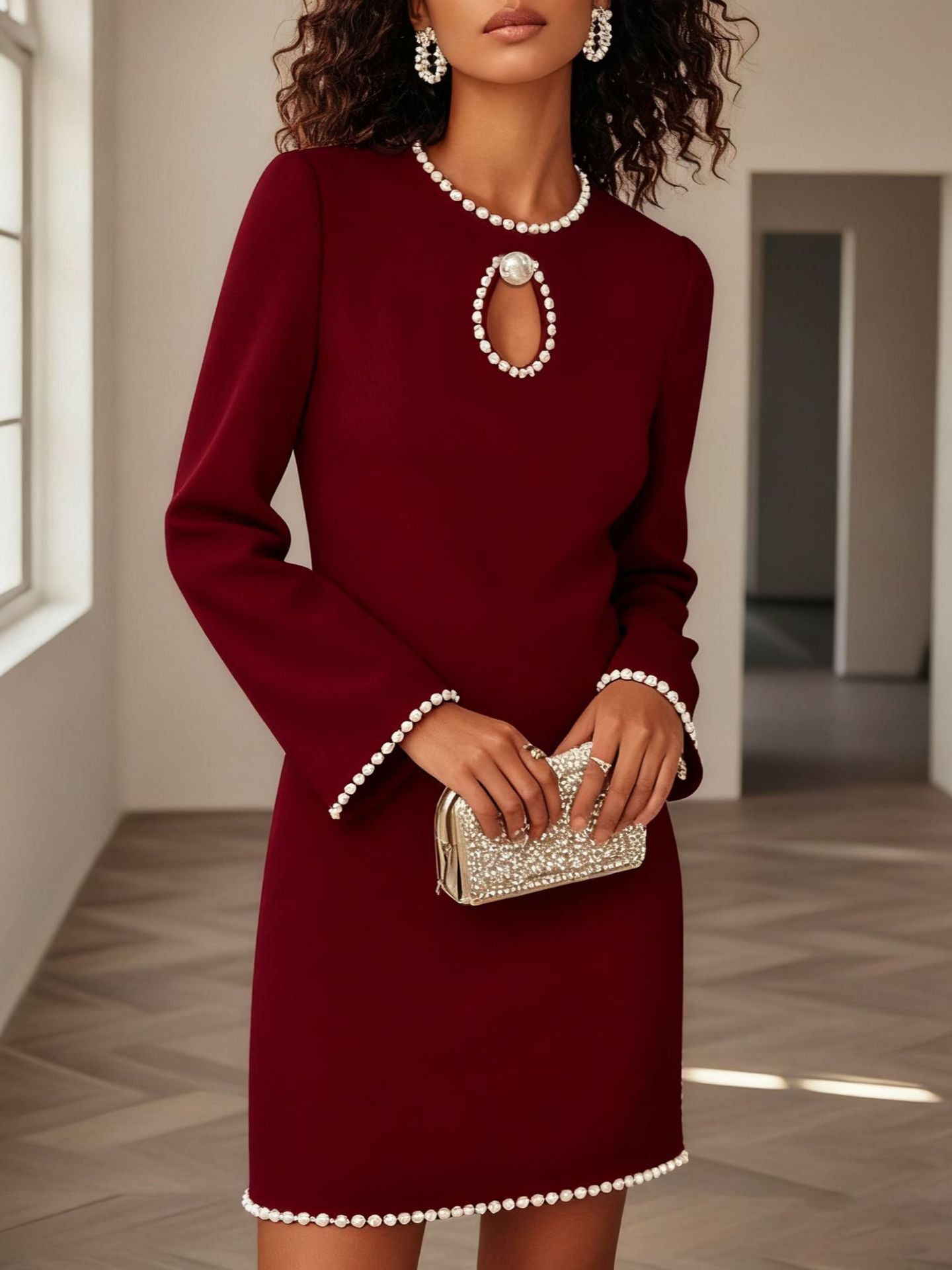 NEWYORKLISTED STYLE COLLECTION: Woman wearing a burgundy dress with pearl details holding a matching clutch.