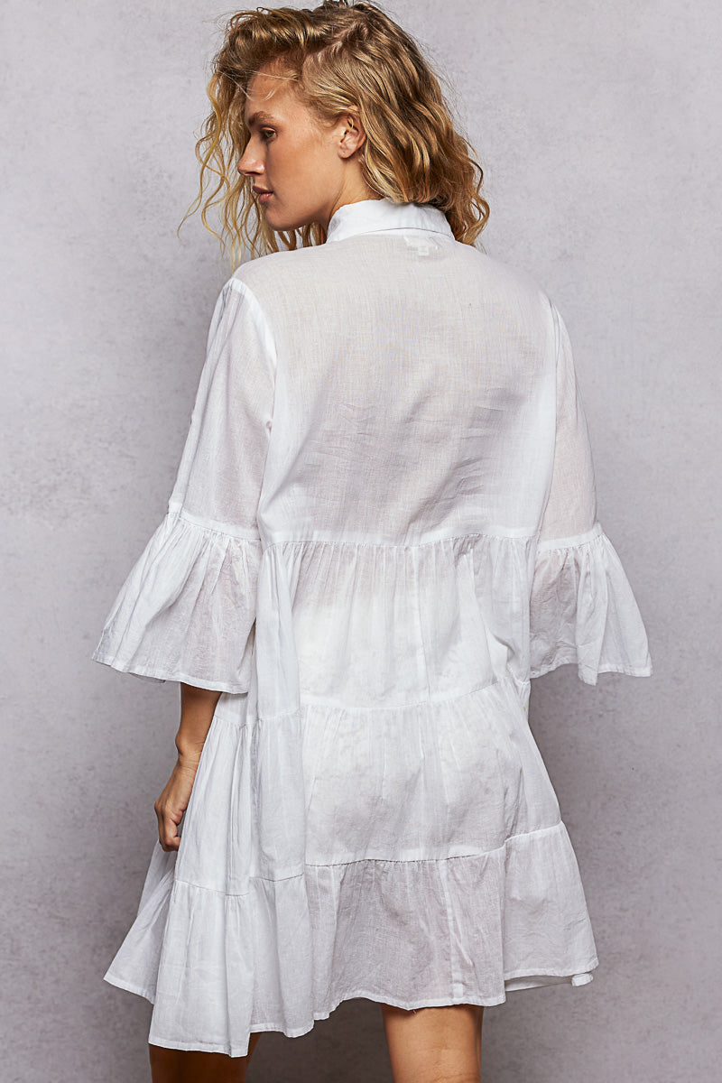 NEWYORKLISTED STYLE COLLECTION: Woman wearing a white dress with ruffled sleeves against a gray background