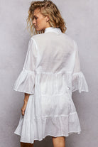 NEWYORKLISTED STYLE COLLECTION: Woman wearing a white dress with ruffled sleeves against a gray background