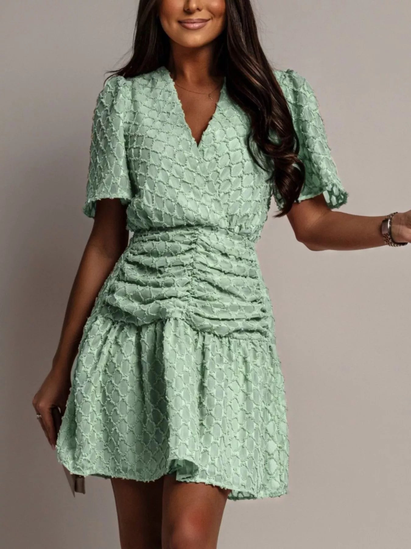 NEWYORKLISTED STYLE COLLECTION: Woman wearing a green textured dress against a neutral background