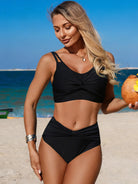 NEWYORKLISTED EDEN COLLECTION: Twist Front High Waisted Swim Set – Ruched Two-Piece Swimsuit in a black bikini holding a pumpkin on a beach