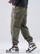 Person wearing olive green cargo pants with a plain background