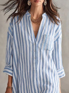 NEWYORKLISTED STYLE COLLECTION: A woman wearing a light blue and white vertically striped button-down shirt with a chest pocket, shown from the shoulders to the hips against a neutral studio background.
