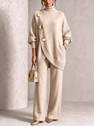 NEWYORKLISTED STYLE COLLECTION:  A woman models a beige knit turtleneck sweater and matching wide-leg trousers set, styled with gold-tone accessories including a metallic handbag and pointed shoes.