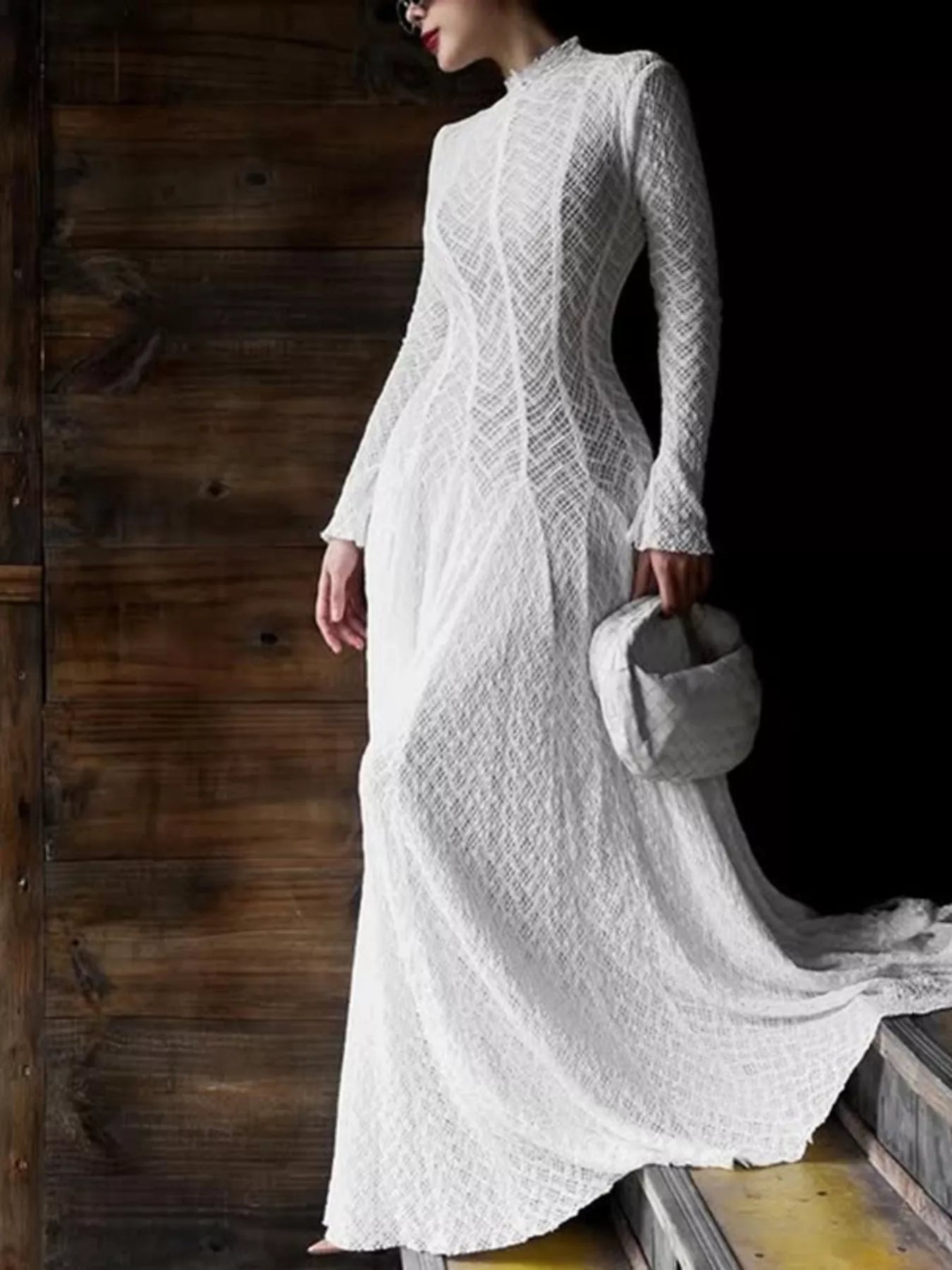 NEWYORKLISTED STYLE COLLECTION: Woman wearing a white lace dress holding a gray bag against a wooden background