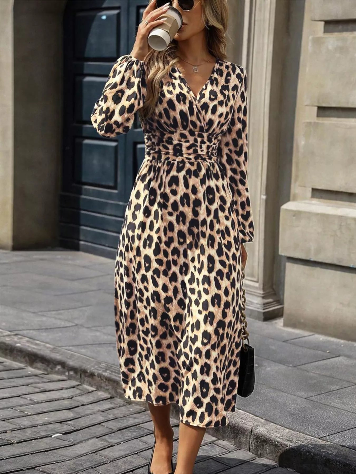 NEWYORKLISTED STYLE COLLECTION: Woman wearing a leopard print dress holding a coffee cup on a city street.