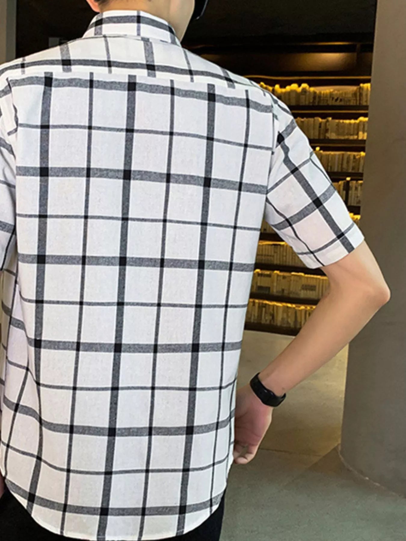 NEWYORKLISTED ATLAS MEN'S COLLECTION: Person wearing a white and black checkered shirt in an indoor setting.