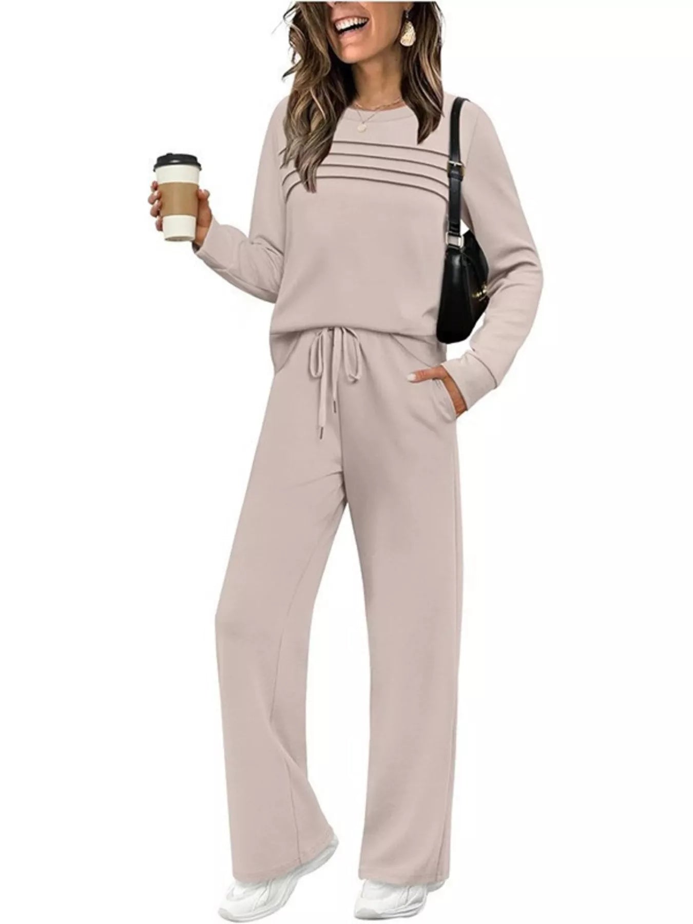 NEWYORKLISTED COMFORT COLLECTION: Woman wearing a beige lounge set holding a coffee cup on a white background
