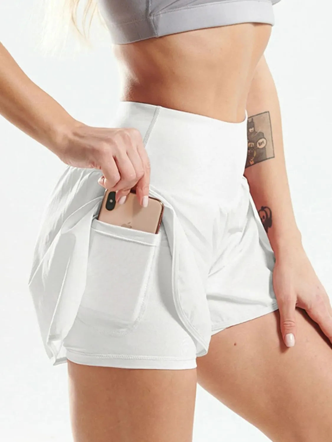 NEWYORKLISTED Activewear: Person wearing white athletic shorts with a pocket holding a phone on a light background