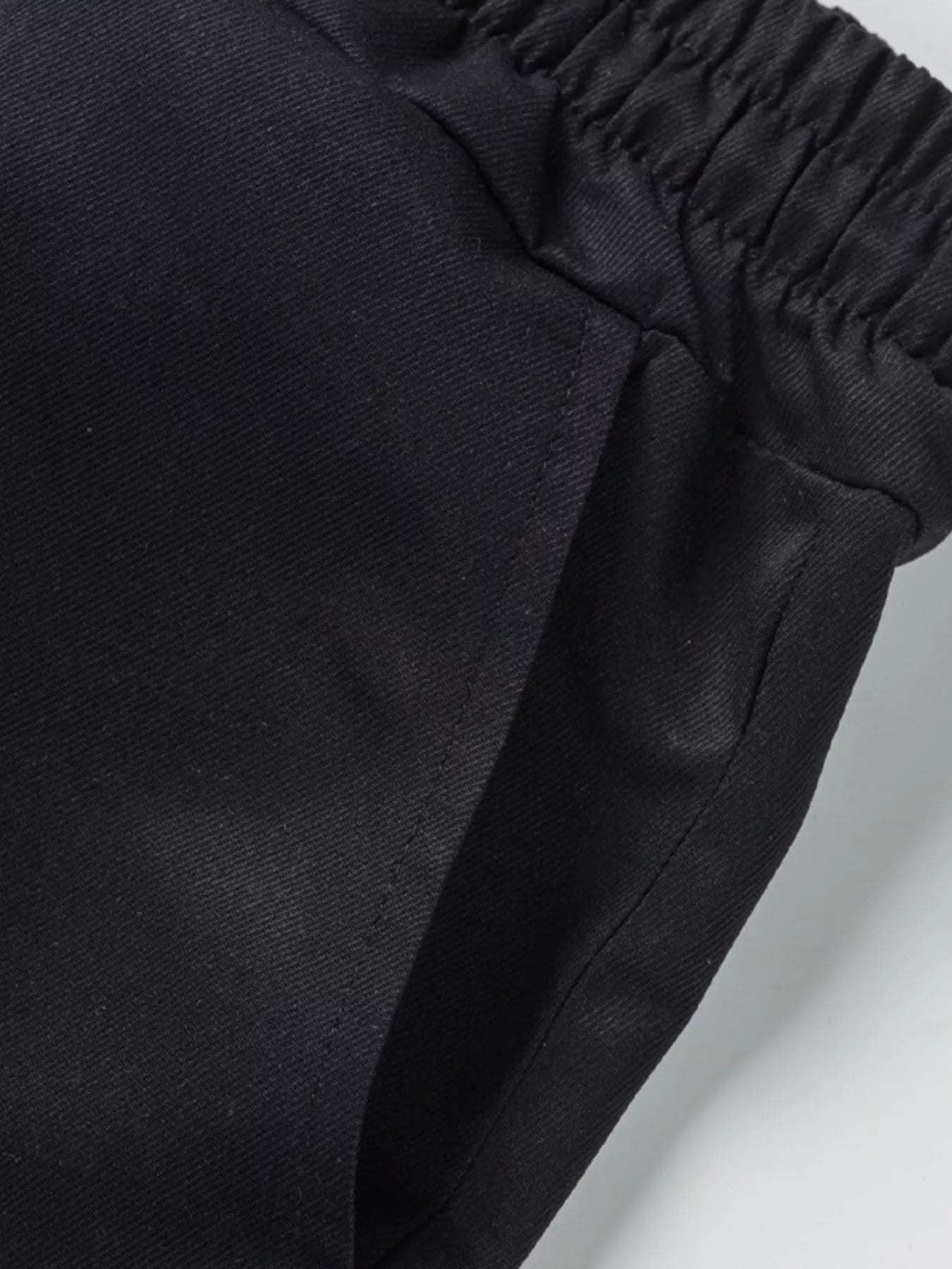 NEWYORKLISTED ATLAS MEN'S COLLECTION: Close-up of black pants with an elastic waistband on a light gray background