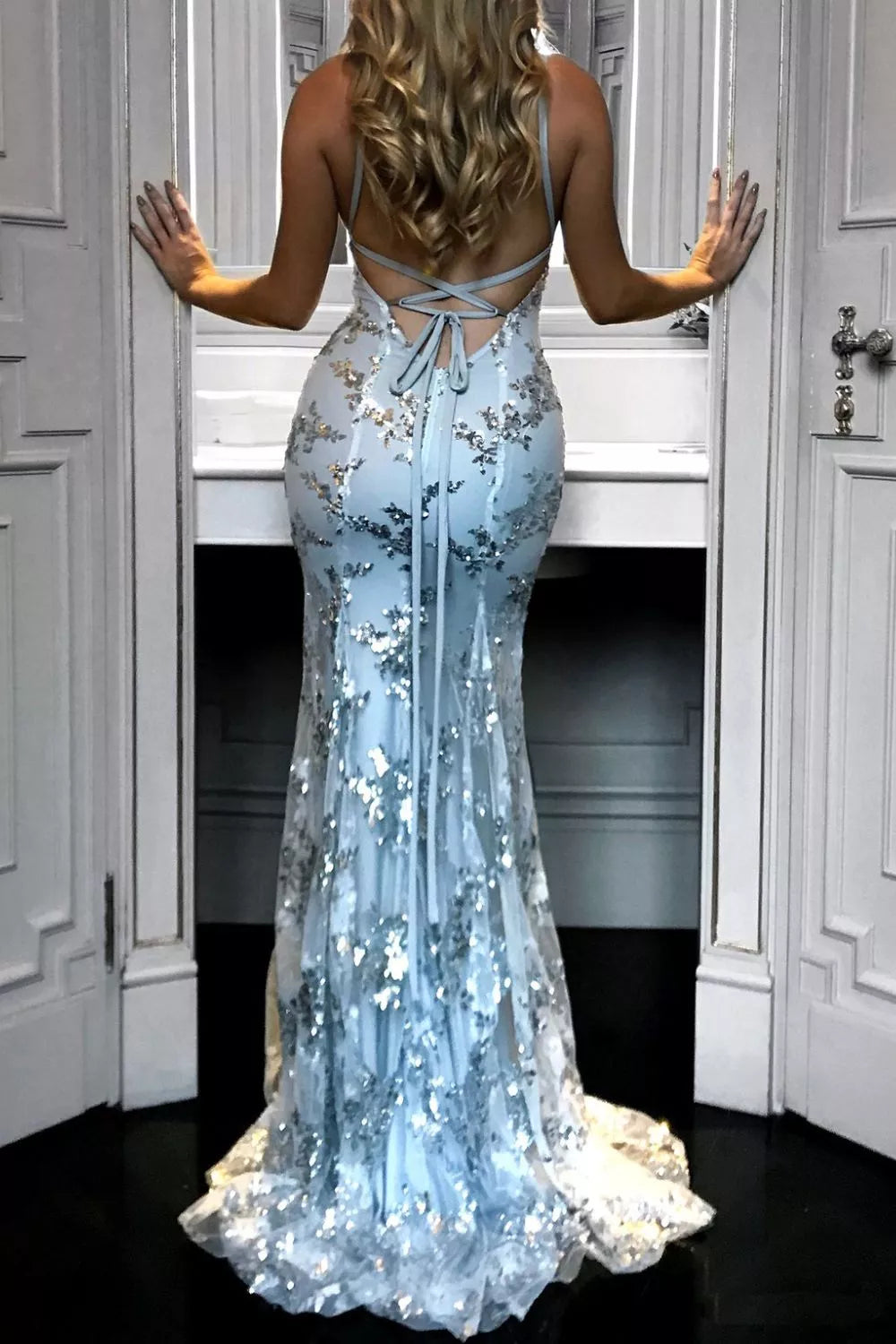 Woman wearing a light blue floral evening gown in a room with white walls and doors.